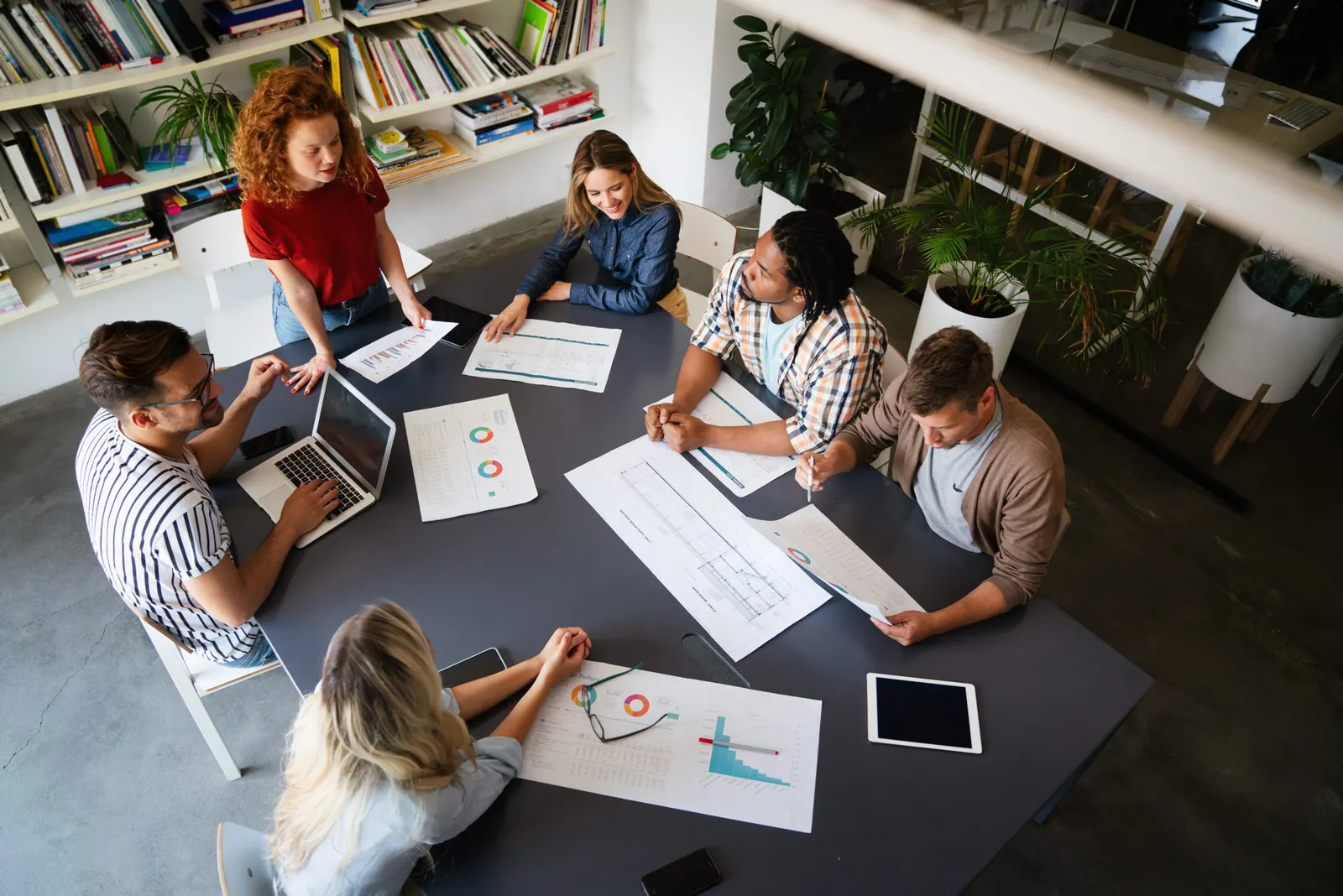 A team reviewing printed charts and reports around a meeting table