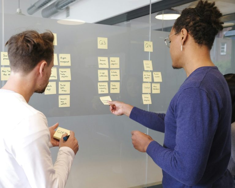Strategy execution at work: two colleagues placing notes on a plan laid out by quarter
